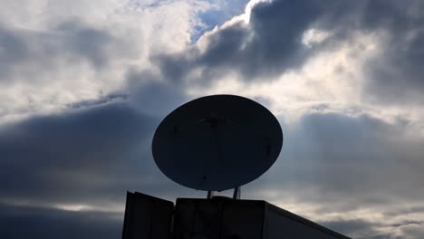 silhouette of a satellite dish against a dramatic cloudy sky