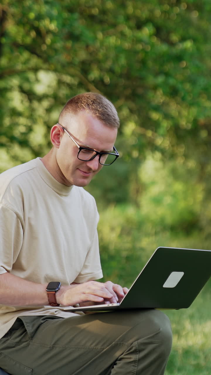 Busy man working in the natural surroundings. Freelancer looks at laptop sitting on the car. Vertical video