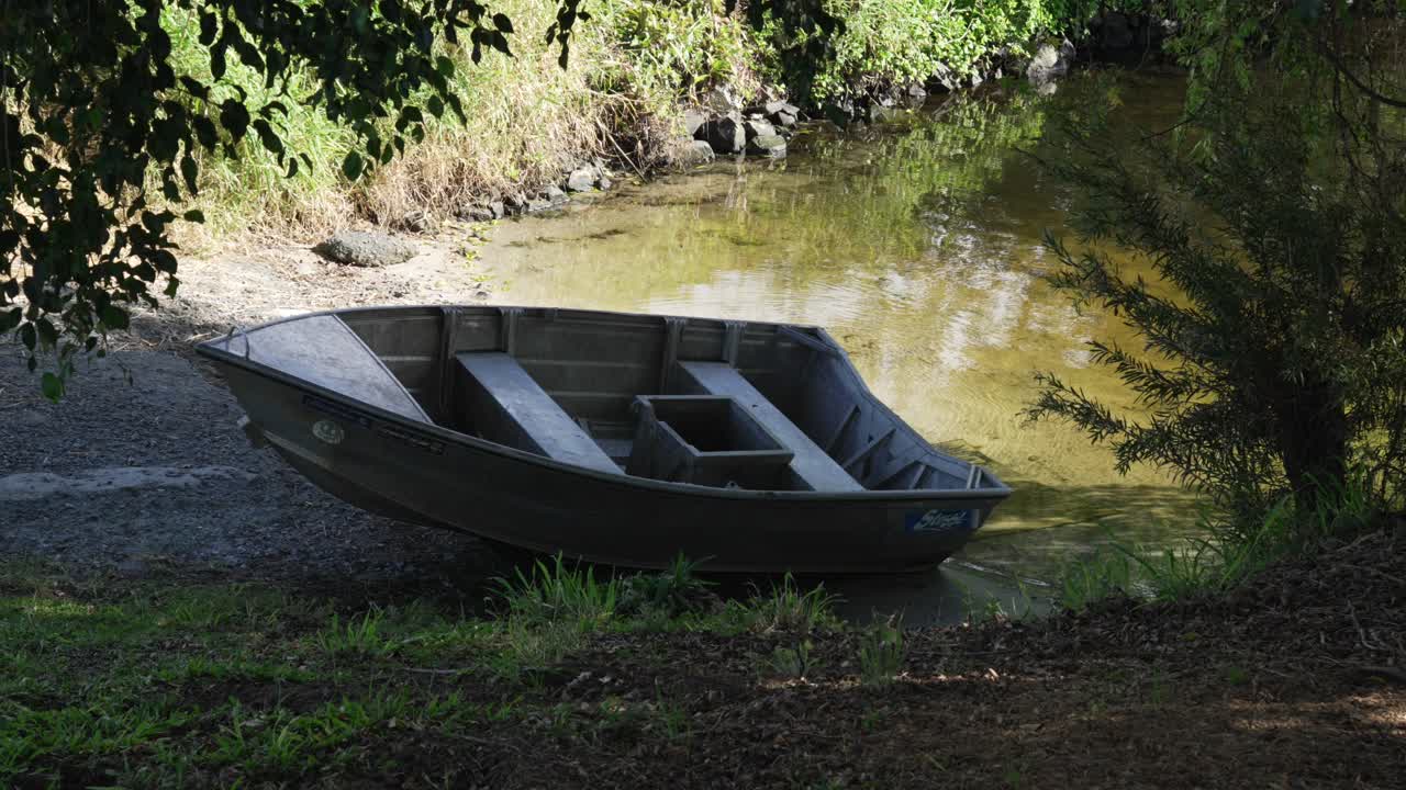 Fishing wooden boat next to shore lake water in Gold Coast Australia forest