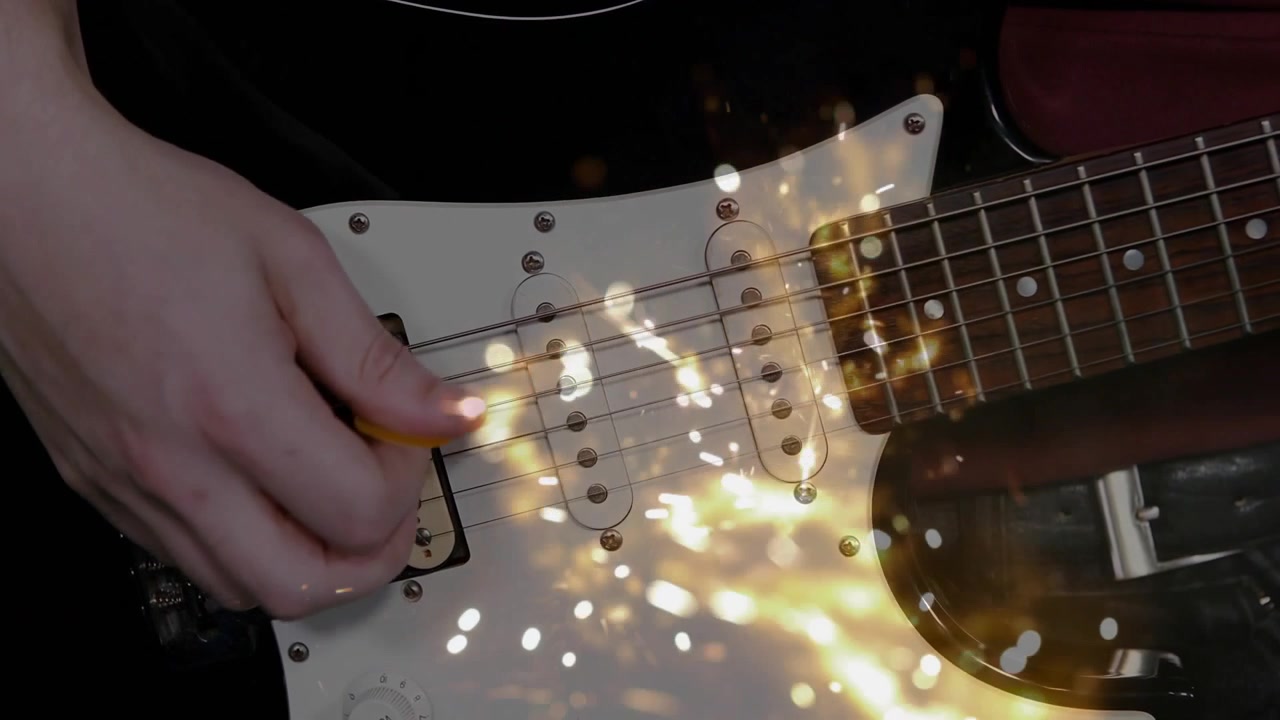 Mano di chitarrista che pizzica il ponte con il plettro, generando scintille intense che si attenuano per la musica sui pickup.