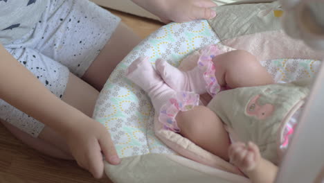 Brother-rocking-baby-sister-in-bouncy-seat