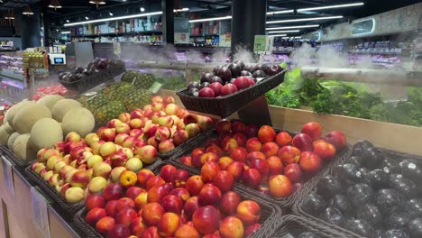 fresh nectarines, plums, cantaloupes and pineapples in the grocery store with cool mist blowing