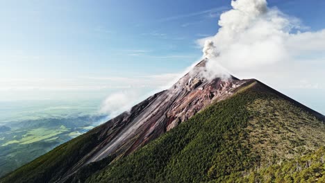 toma aérea del volcán de fuego que hace erupción de ceniza durante un día claro y soleado en guatemala