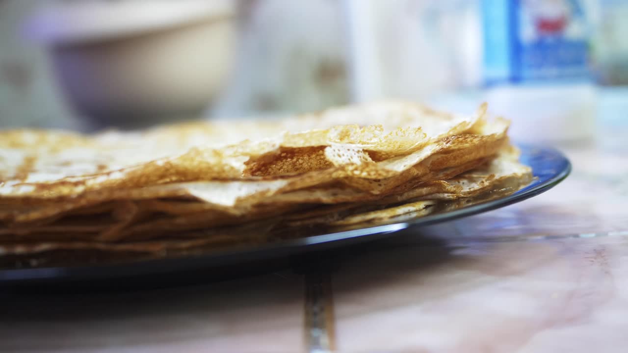 A hand carefully lifts a freshly made crepe. The close-up highlights the crepe’s appealing texture and golden color