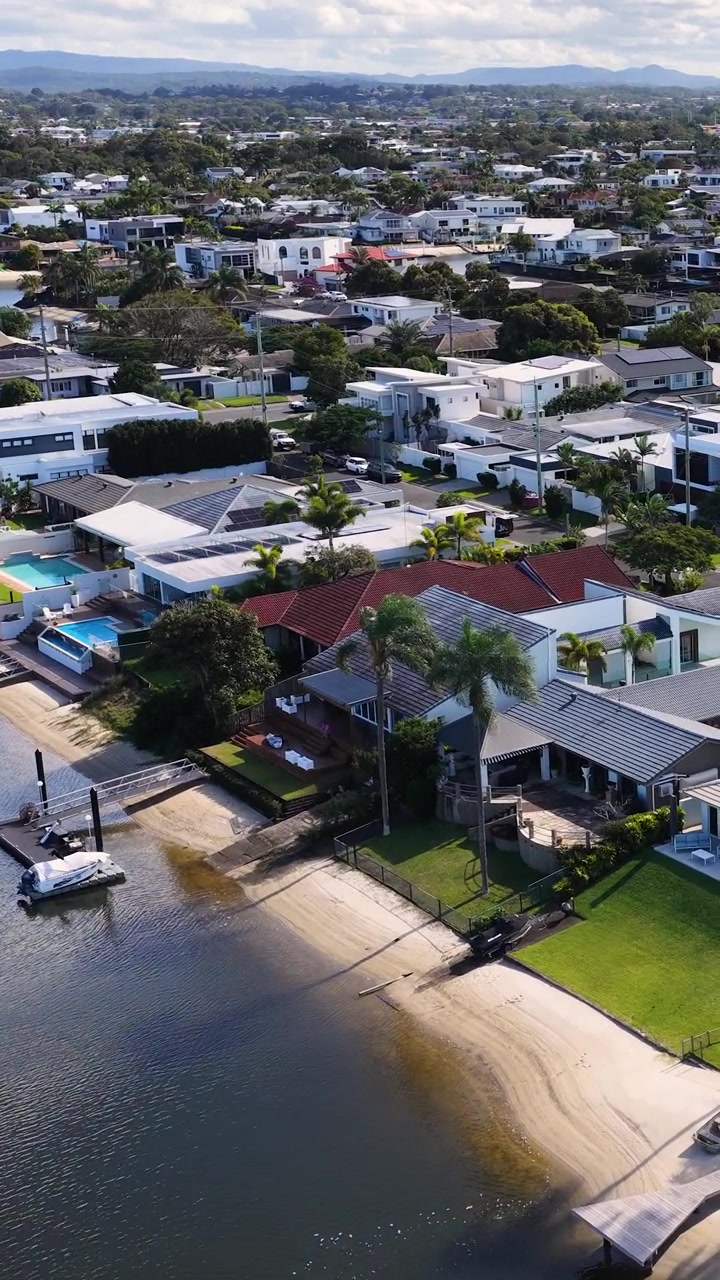Plano cenital de dron haciendo un paneo sobre viviendas residenciales de lujo a lo largo de un canal costero