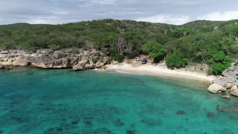 Drone-flying-around-private-beach-with-clear-blue-ocean-water