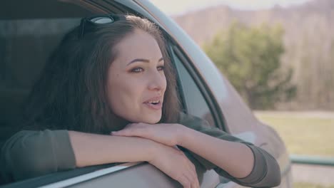 brunette-with-sunglasses-on-head-looks-out-of-modern-car