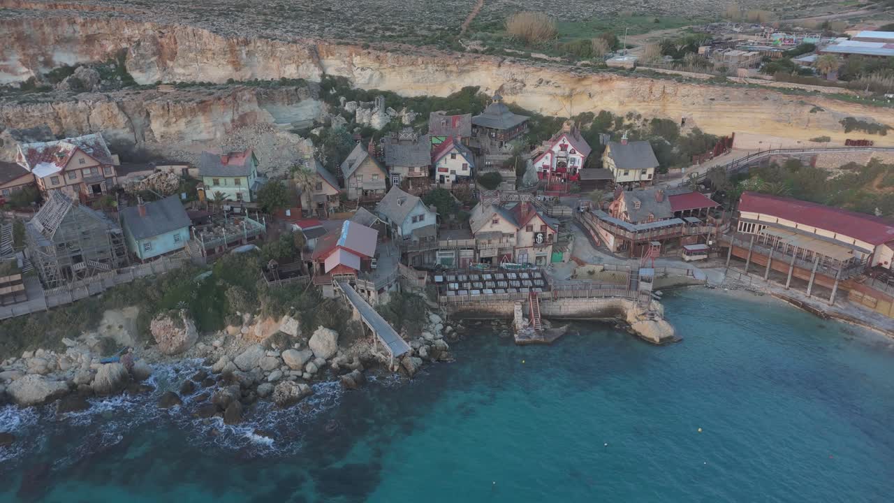 Establishing aerial at Popeye Village Malta coastal town, blue azure water of European travel destination