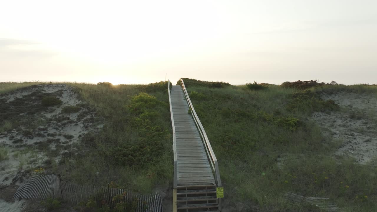 Golden sunrise over Ogunquit Beach, Maine with a peaceful boardwalk leading through dunes to the ocean—serene and scenic coastal moment.