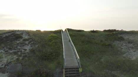 golden sunrise over ogunquit beach, maine with a peaceful boardwalk leading through dunes to the ocean—serene and scenic coastal moment.