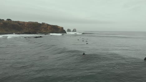 Toma-Aérea-De-Drones-Que-Avanza-Sobre-Los-Surfistas-En-Un-Día-Frío-En-El-Mar,-Pichilemu,-Chile-4k