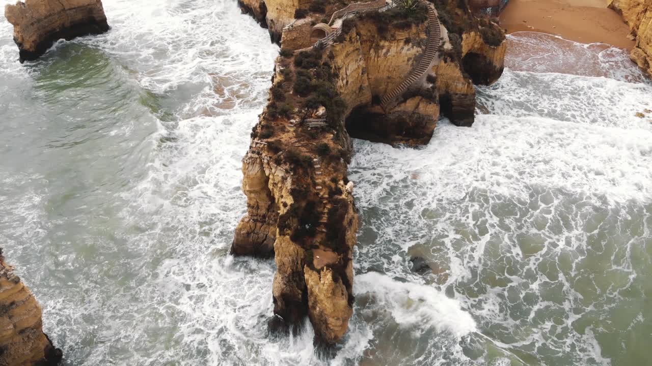 paseo de los acantilados rocosos del algarve conectado por un puente de piedra en la costa del océano en la playa de estudiantes en lagos, portugal - sobrevuelo de vista aérea superior