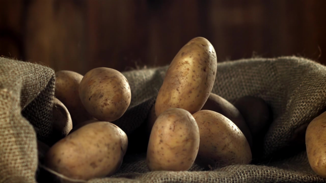 Patate crude che cadono in un sacco di iuta al rallentatore