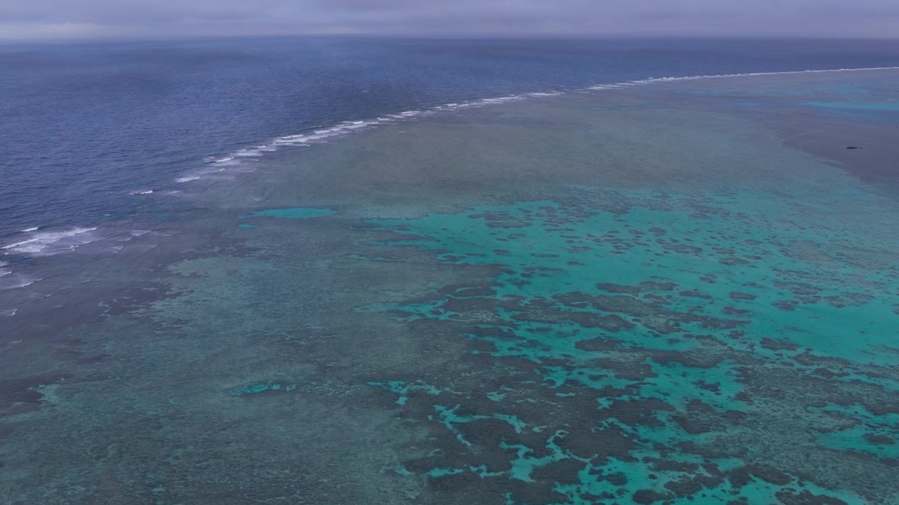Inquadratura orizzontale con carrello in avanti da un'angolazione obliqua elevata sopra la barriera corallina poco profonda vicino alla spiaggia di Hirano, Ishigaki, Okinawa, Giappone