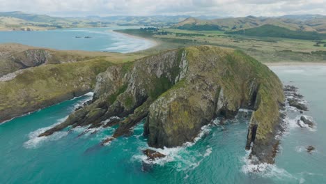 vista aérea de drones de la impresionante bahía de los caníbales con paisajes costeros escarpados y salvajes y aguas oceánicas turquesas en catlins, isla sur de nueva zelanda aotearoa