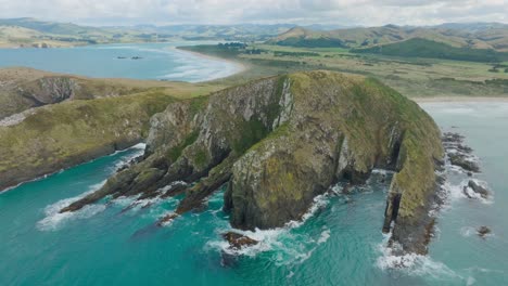 aerial drone view of stunning cannibal bay with rugged and wild coastal landscape and turquoise ocean water in catlins, south island of new zealand aotearoa