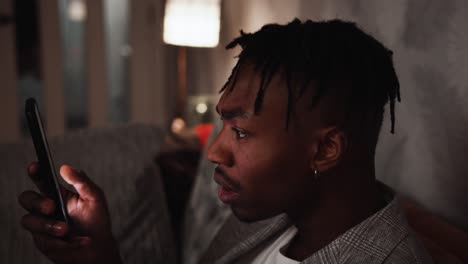young black male becomes shocked while looking at smart phone at home
