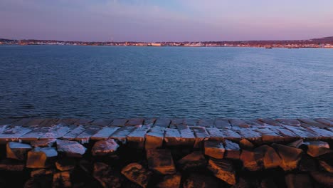 Cerrar-Diapositiva-Aérea-A-Lo-Largo-De-Un-Rompeolas-Rocoso-Polvo-De-Nieve-En-Rockland-Maine