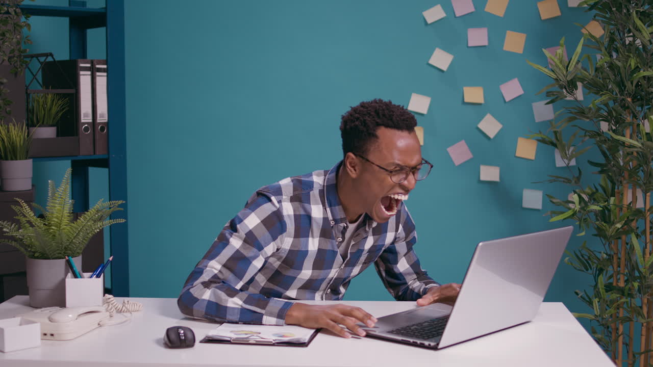 Angry employee shouting at laptop screen feeling frustrated