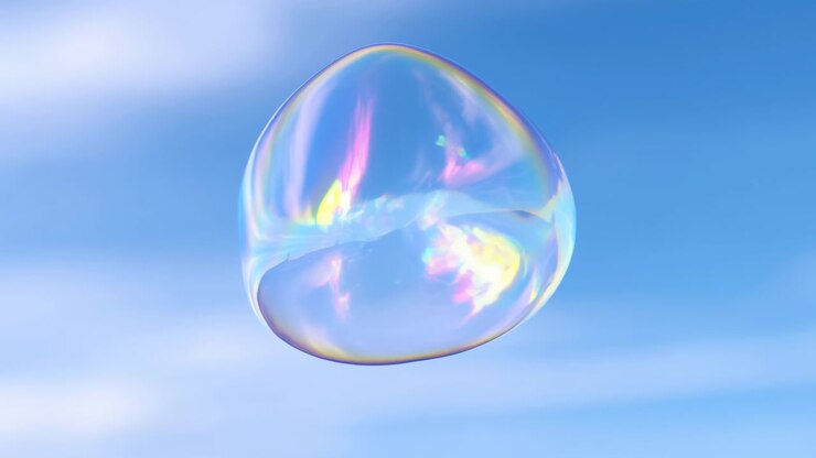 Single floating bubble shifts between oval and rounded shapes as pink, yellow and cyan highlights ripple over its delicate surface, framed by soft clouds and bright blue sky with open space.