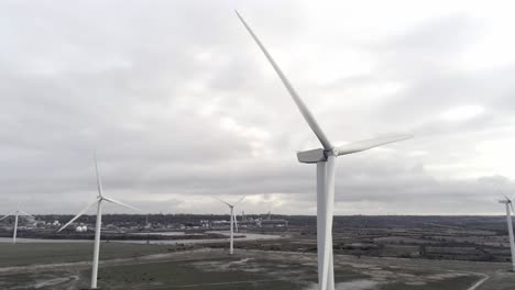 Sustainable-electrical-wind-turbines-spinning-on-England-farmland-aerial-orbit-left