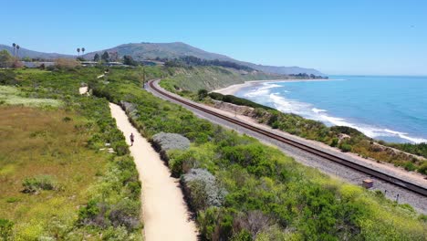 aerial over man jogging runner exercise along coastal trail railroad tracks and the pacific coast near santa barbara 1