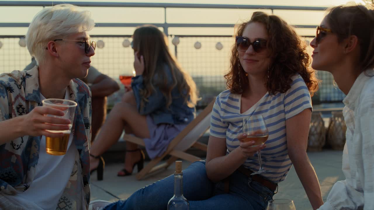 Group of caucasian friends sitting and talking together at the rooftop in summer day.