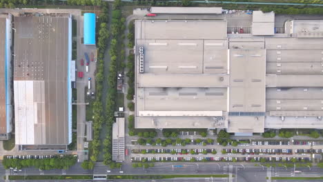 overhead shot of industrial big factory warehouse rooftop. aerial drone shot camera flying forward. factory rooftop, roof windows, ventilation shafts, flat roof of a big manufacture warehouse.