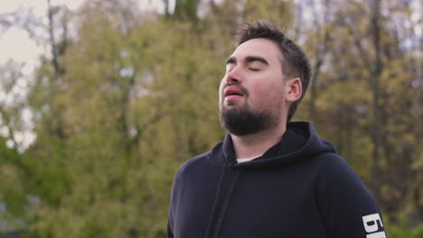 relaxed bearded man breathing fresh air standing in the park in the morning