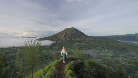 戴着传统纱袍的金发女人在卡尤帕迪观景点,举起手来致敬,巴图尔山火山口