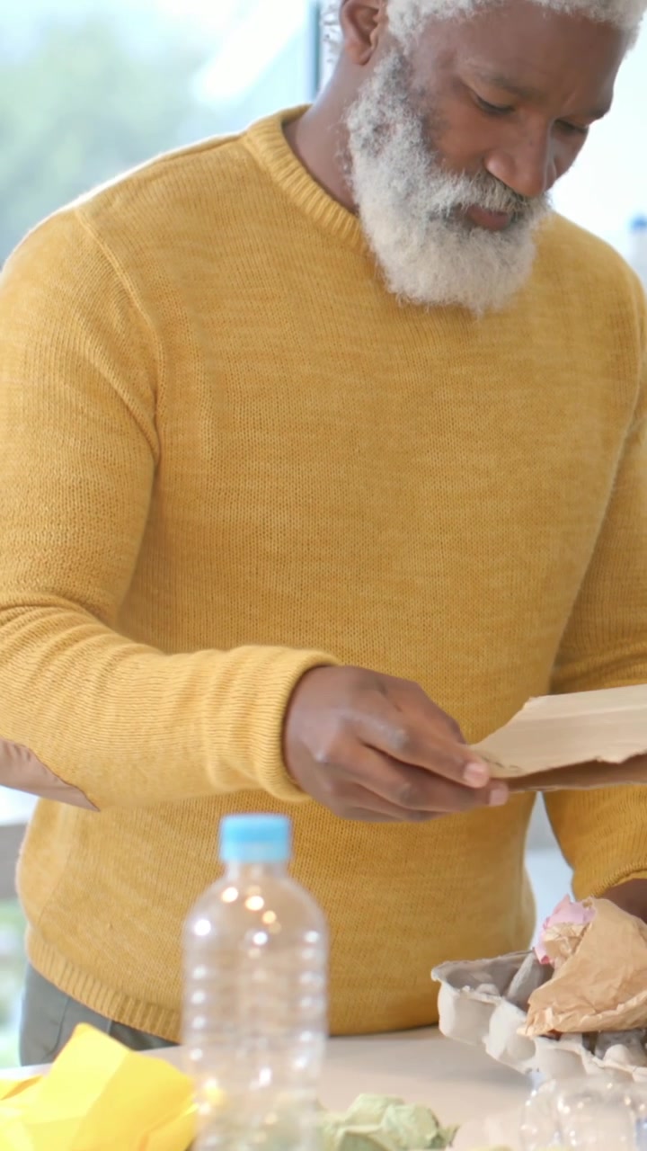 Vertical video: Reaching across kitchen counter man in mustard sweater preparing eggs and bottle