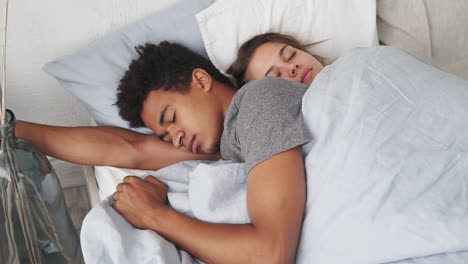 close up view of multiracial couple lying in bed and sleeping while embracing each other. young family concept