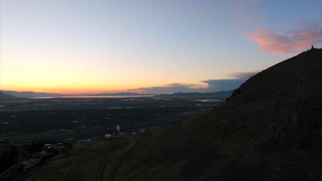 Drone-Elevándose-En-Una-Colina-Con-El-área-Industrial-De-Salt-Lake-City-Al-Fondo-Al-Atardecer,-Utah-En-EE.UU.