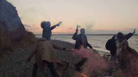 Group-Of-Teenage-Friends-Running-Around-A-Bonfire-Holding-Colored-Sparklers-On-The-Seashore-1