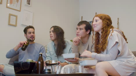 Amigos-Sentados-En-El-Sofá,-Viendo-Televisión,-Hablando-Y-Comiendo-Patatas-Fritas