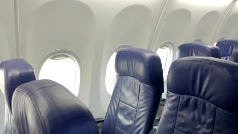 interior de la cabina de un avión comercial con asientos de pasajeros azules.