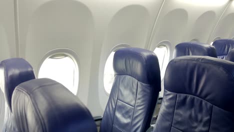 interior of commercial airplane cabin with blue passenger seats.