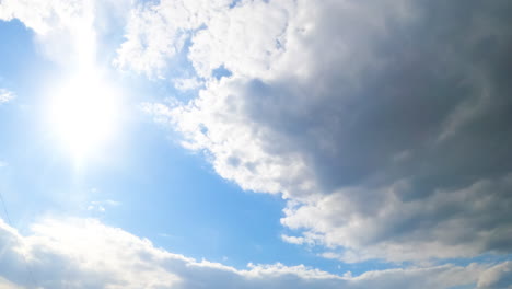bright sun in the blue summer skies. big grey cloud approaches to hide the sun. view from below. timelapse.