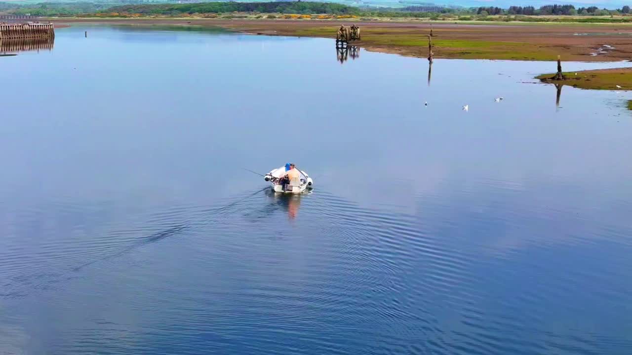 Aerial view, man fishing from a small boat on calm reflective water, creating ripples on a peaceful day outdoors