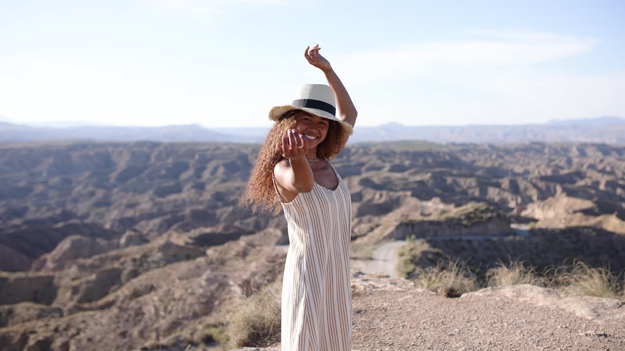 Young woman posing on a cliff overlooking a vast desert landscape