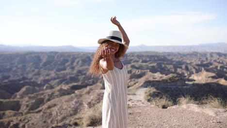 young woman posing on a cliff overlooking a vast desert landscape