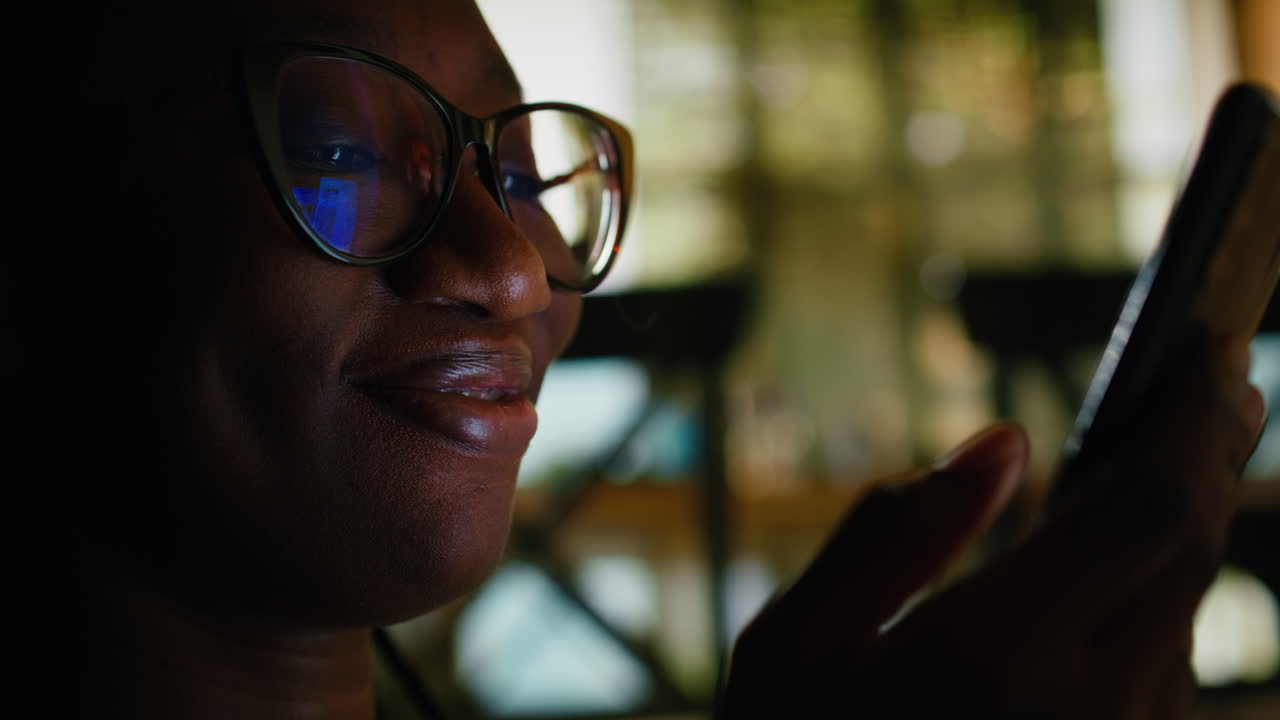 African American young adult relaxing at home with her smartphone