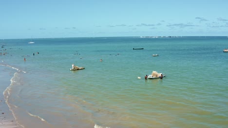 dolly en toma aérea de pequeños barcos de pesca que se preparan para zarpar en la orilla de la playa de bessa en la capital tropical joao pessoa, brasil en el estado de paraiba en un cálido día soleado de verano
