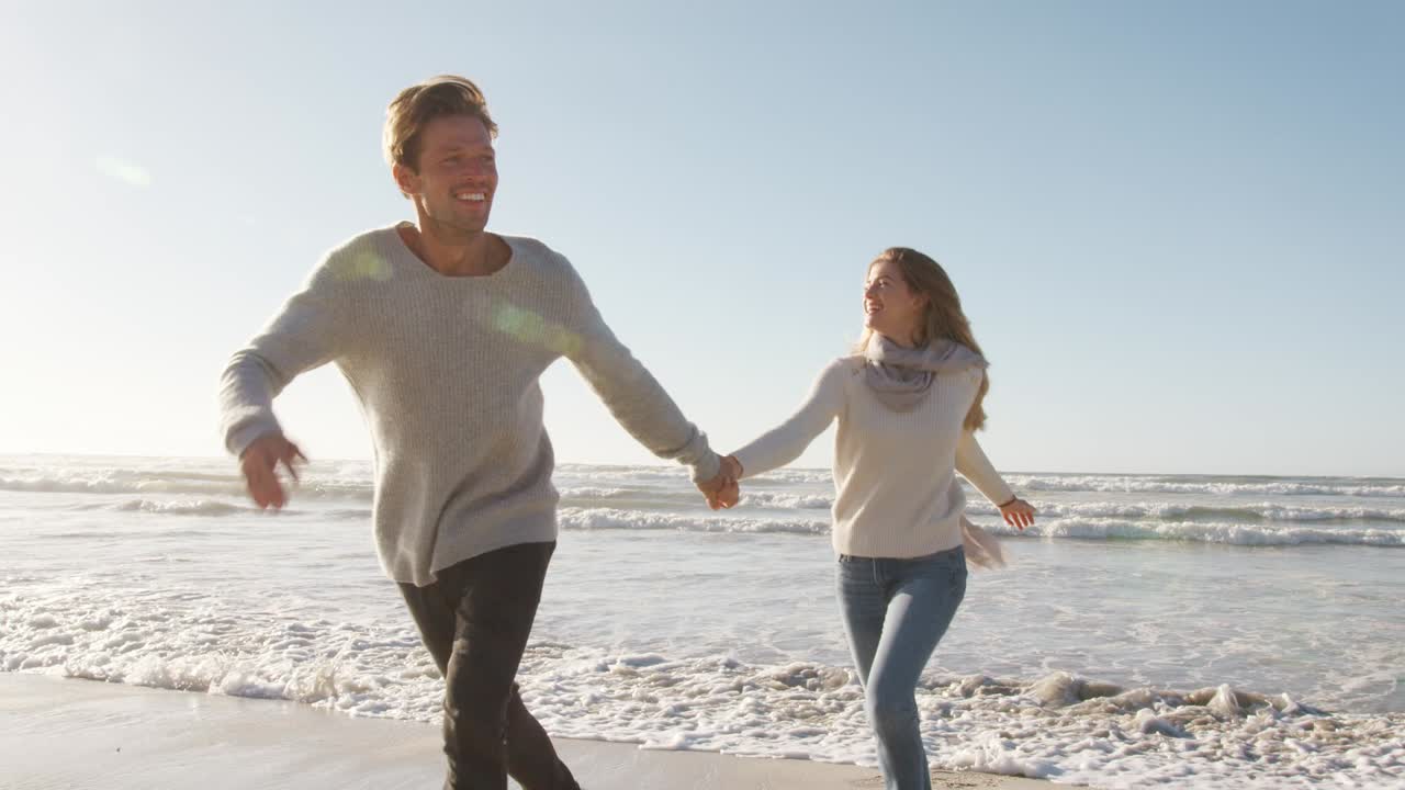 재미 있는 커플 이 함께 겨울 해변 을 따라 달리고 있다