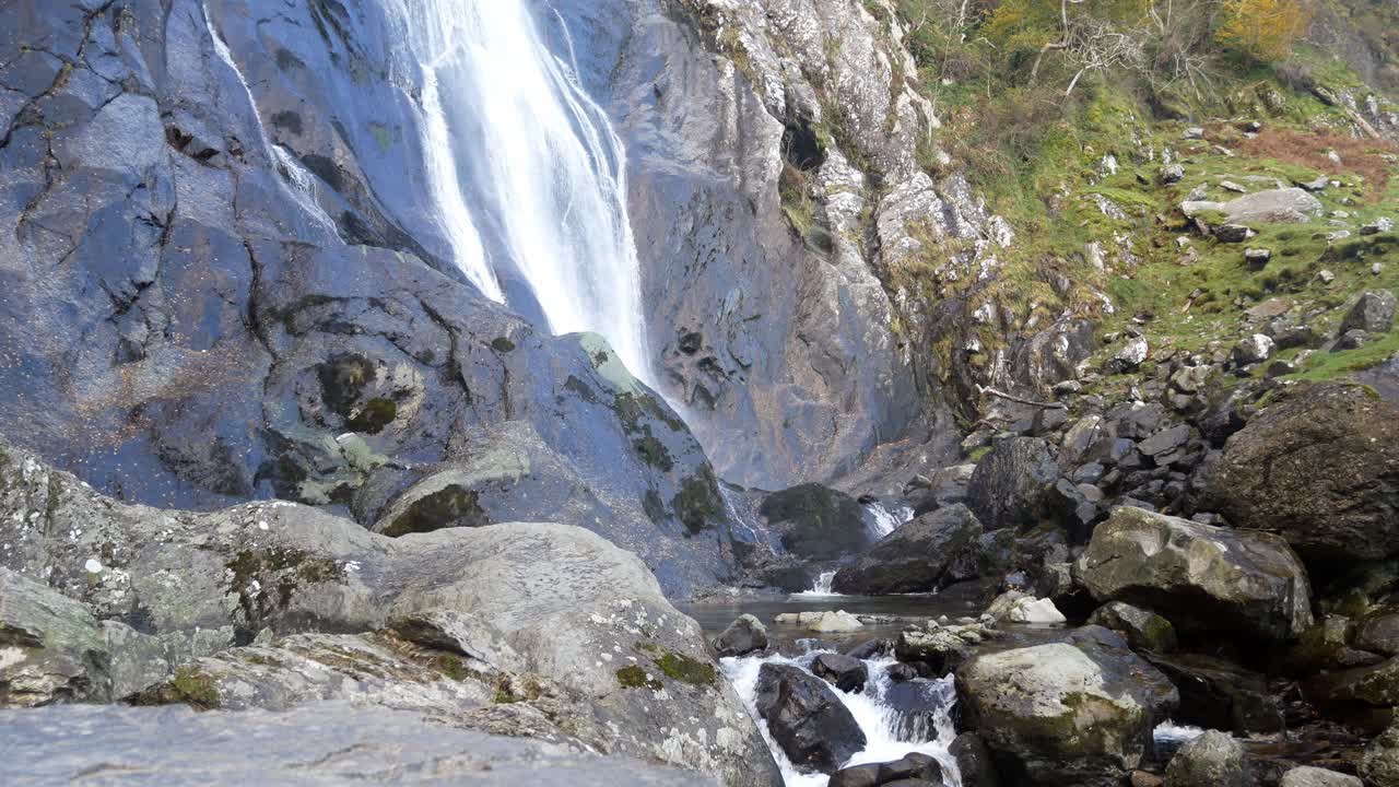 cascada rocosa que fluye hacia las rocas del río dentadas dolly justo a través de los cantos rodados