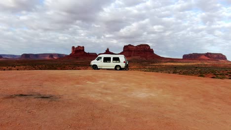 drone shot flying towards van lifers and a woman exercising in monument valley