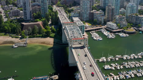 traffic driving at four-lane burrard bridge with moored boats in marina by false creek - reveal shot of downtown vancouver skyline in canada