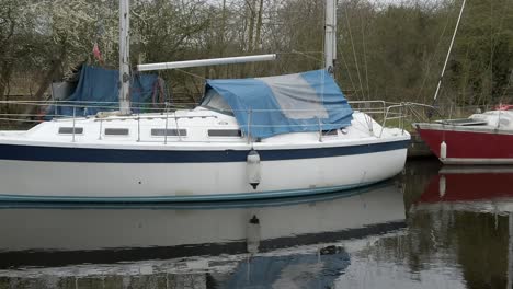 Small-sailboats-moored-on-narrow-rural-countryside-canal-harbour