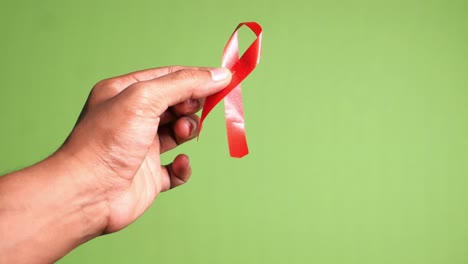 hand holding a red ribbon for aids awareness