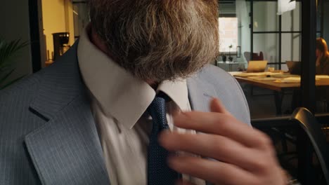 businessman adjusting tie in office